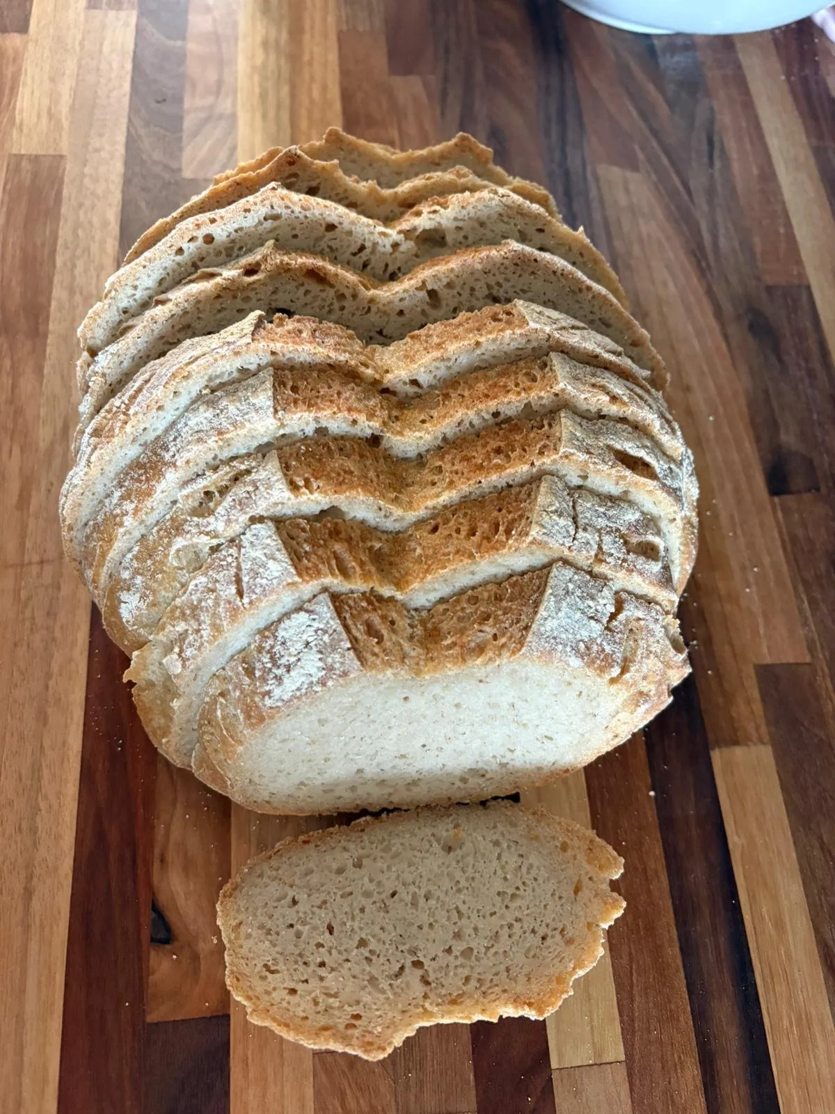 Standing sliced sourdough loaf with a single slice in front